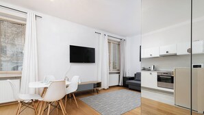 A modern apartment with a dining area, kitchen, and a TV mounted on the wall. - RentPlanet - Apartament Chmielna (Warsaw)