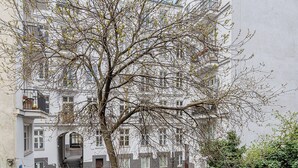 A courtyard with a tree in the center, surrounded by buildings with balconies and windows. - RentPlanet - Apartament Chmielna (Warsaw)