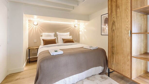 A modern bedroom with a large bed, wooden wardrobe, and a nightstand. - Superb Air-conditioned Duplex - Bastille Le Marais (Paris)