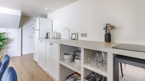 A modern kitchen with white cabinets, a built-in oven, and a countertop with a kettle and toaster. - Superb Air-conditioned Duplex - Bastille Le Marais (Paris)