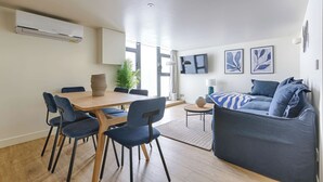 A modern living room with a sofa, a dining table with chairs, and a small side table. - Superb Air-conditioned Duplex - Bastille Le Marais (Paris)