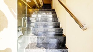 A staircase with black marble steps and a glass door on the left. - Super Hotel O Somnath Formerly Hotel Somnath Tirth (Veraval)