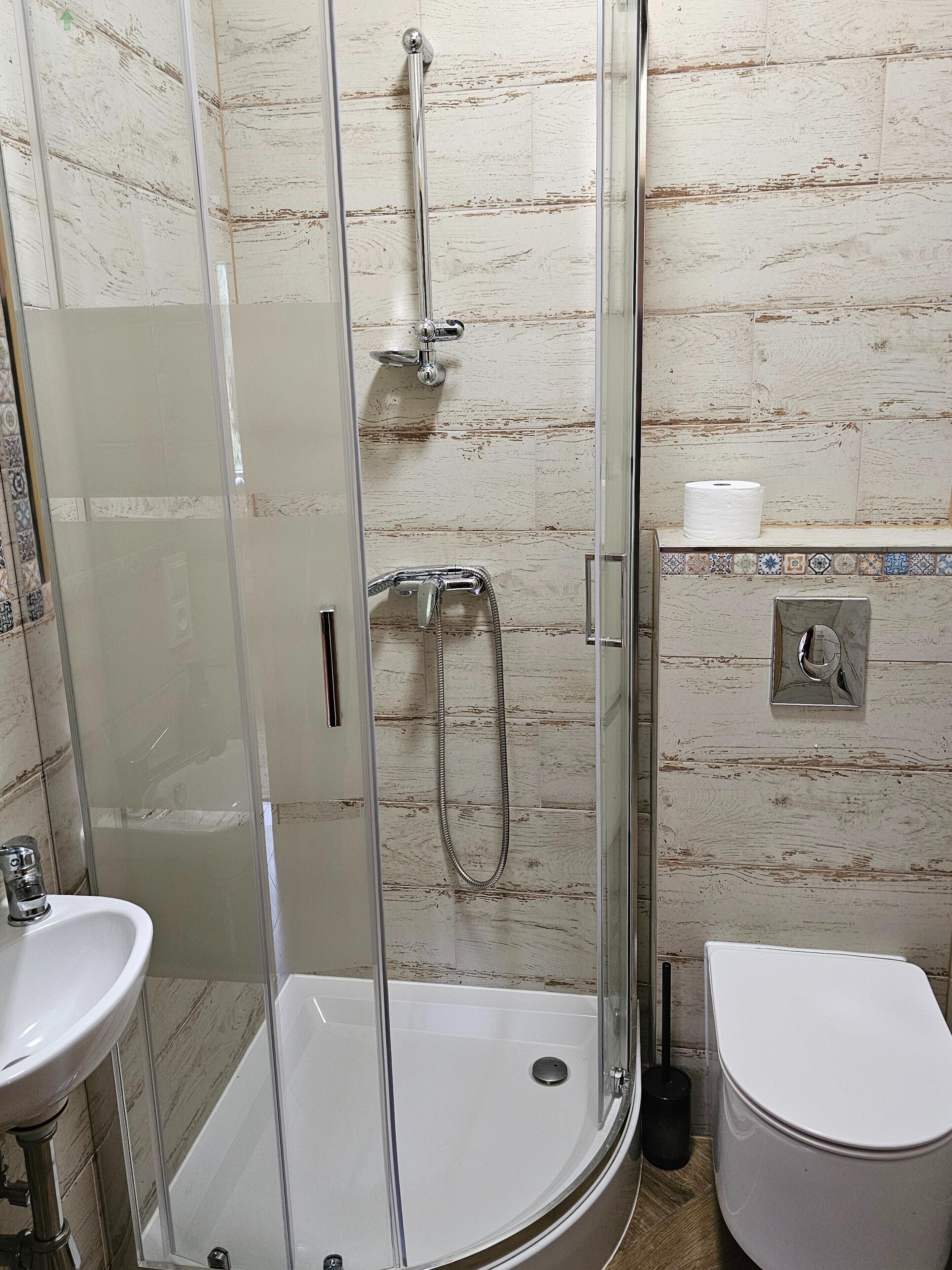 Ein Badezimmer mit Duschkabine, Waschbecken und Toilette.