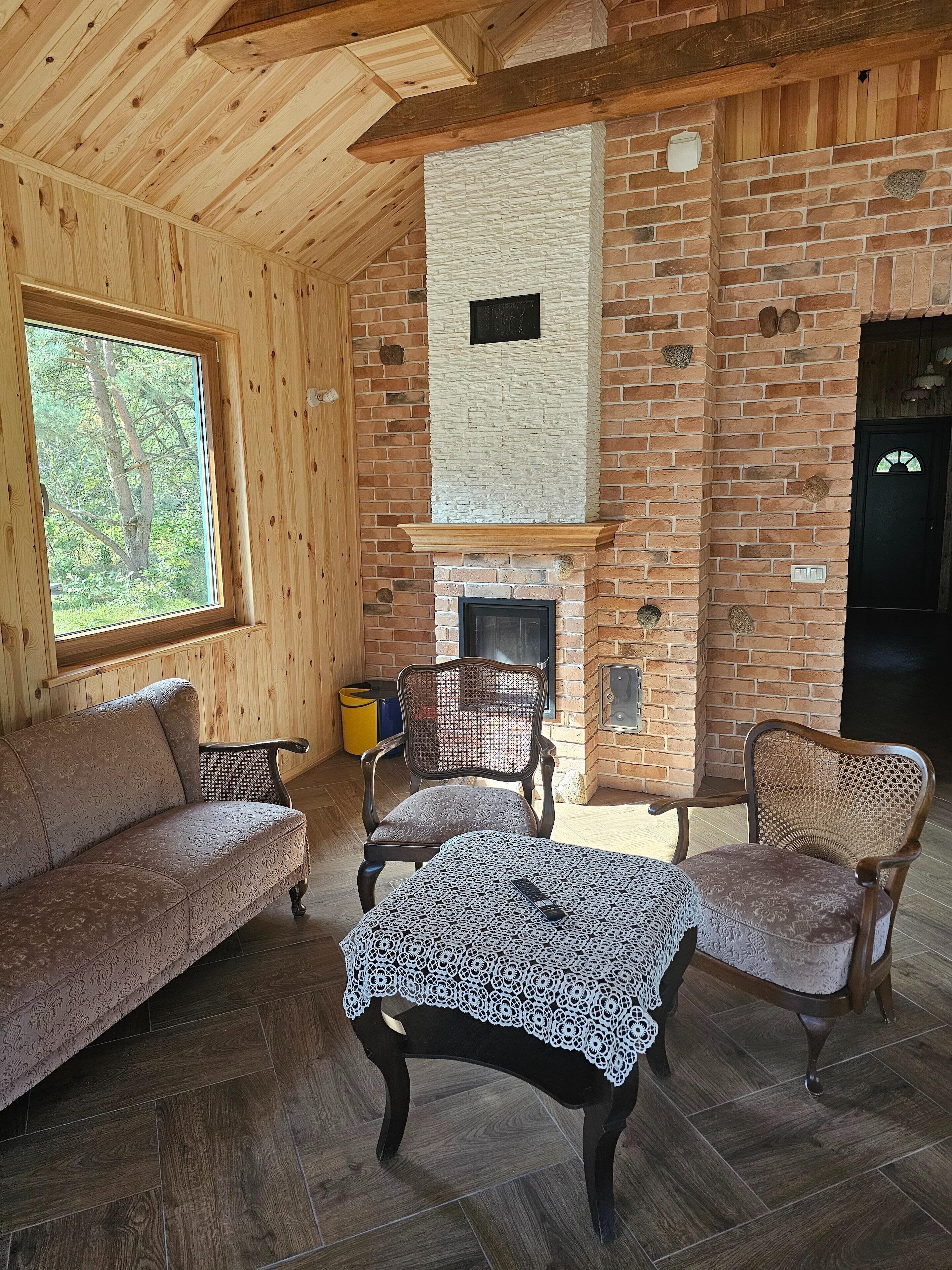A cozy room with a fireplace, wooden walls, a sofa, and a table.