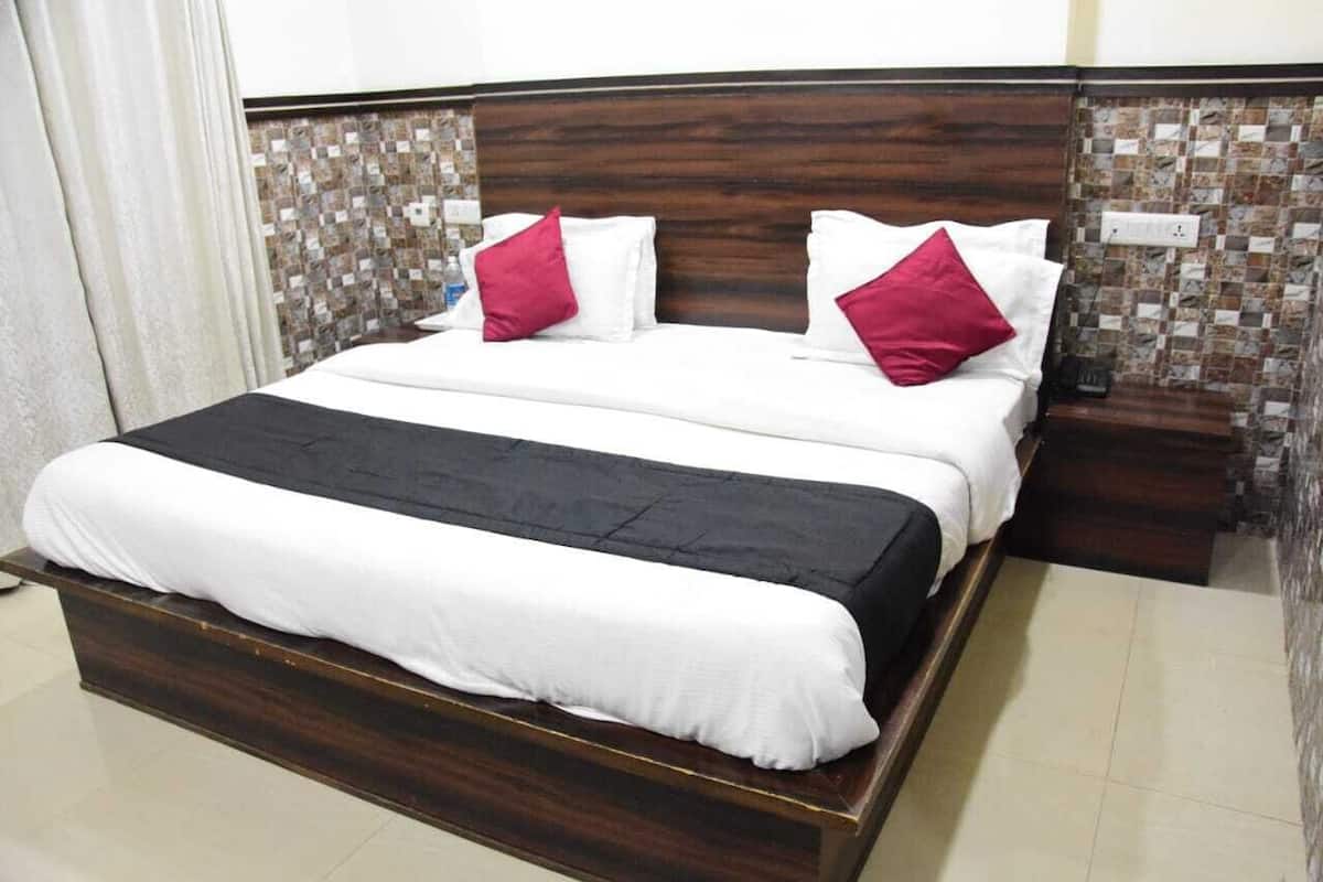 A bed with a dark wooden frame, white bedding, and two red pillows.