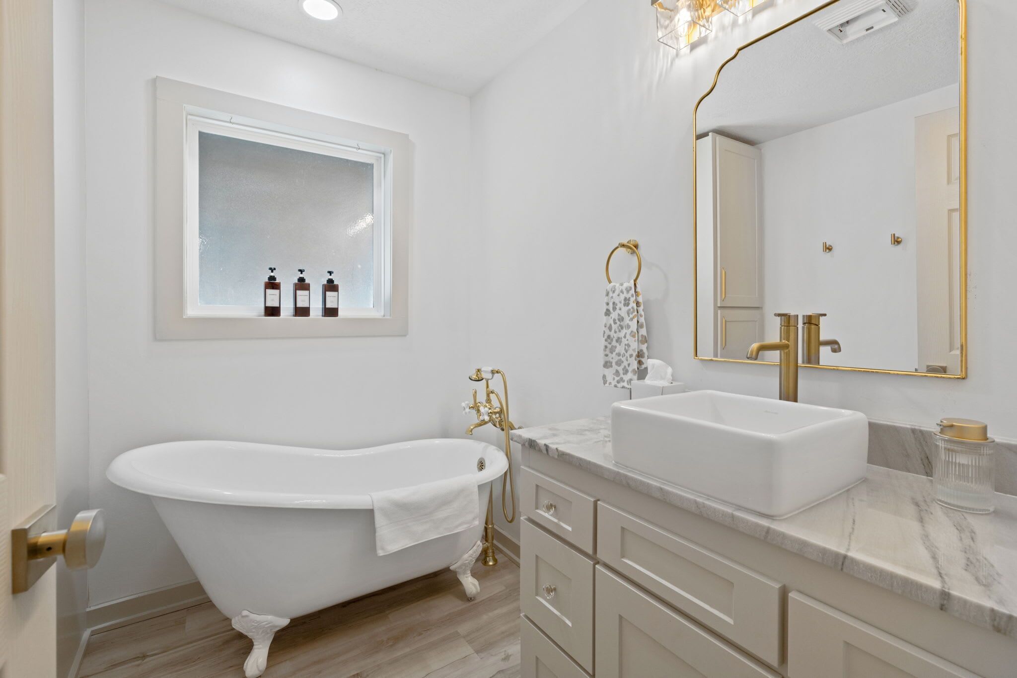 A modern bathroom with a freestanding bathtub, a double sink vanity, and a large mirror with a gold frame.
