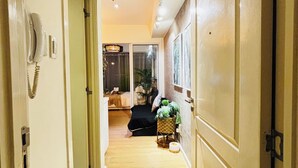 A hallway with a wooden floor, a doormat, and a door with a telephone. - Cozy 1-bedroom apartment in pleasant Parañaque with AC (Parañaque)