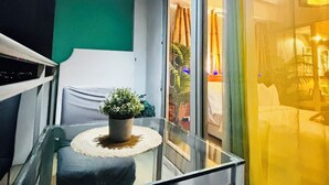 A balcony with a glass table, a potted plant, and a view of the interior through a glass door. - Cozy 1-bedroom apartment in pleasant Parañaque with AC (Parañaque)