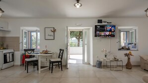Uma sala de estar moderna com área de jantar, TV fixada na parede e vista através de uma porta aberta.