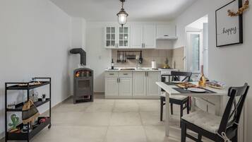 A modern kitchen with white cabinets, a dining area with a table and chairs, and a small cart with items.
