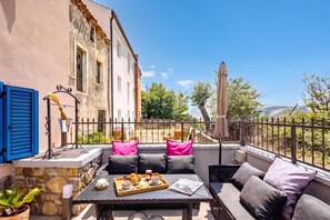 An outdoor seating area with a table set for breakfast, a stone wall, and a view of a building and trees. - Harmony House Vito With Lovely Terrace (Lopar)