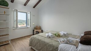 Quarto com cama, janela, estante e vista para o exterior.