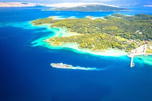 An aerial view of a coastal area with a cruise ship docked near a pier, surrounded by turquoise waters and lush green islands. - Harmony House Vito With Lovely Terrace (Lopar)