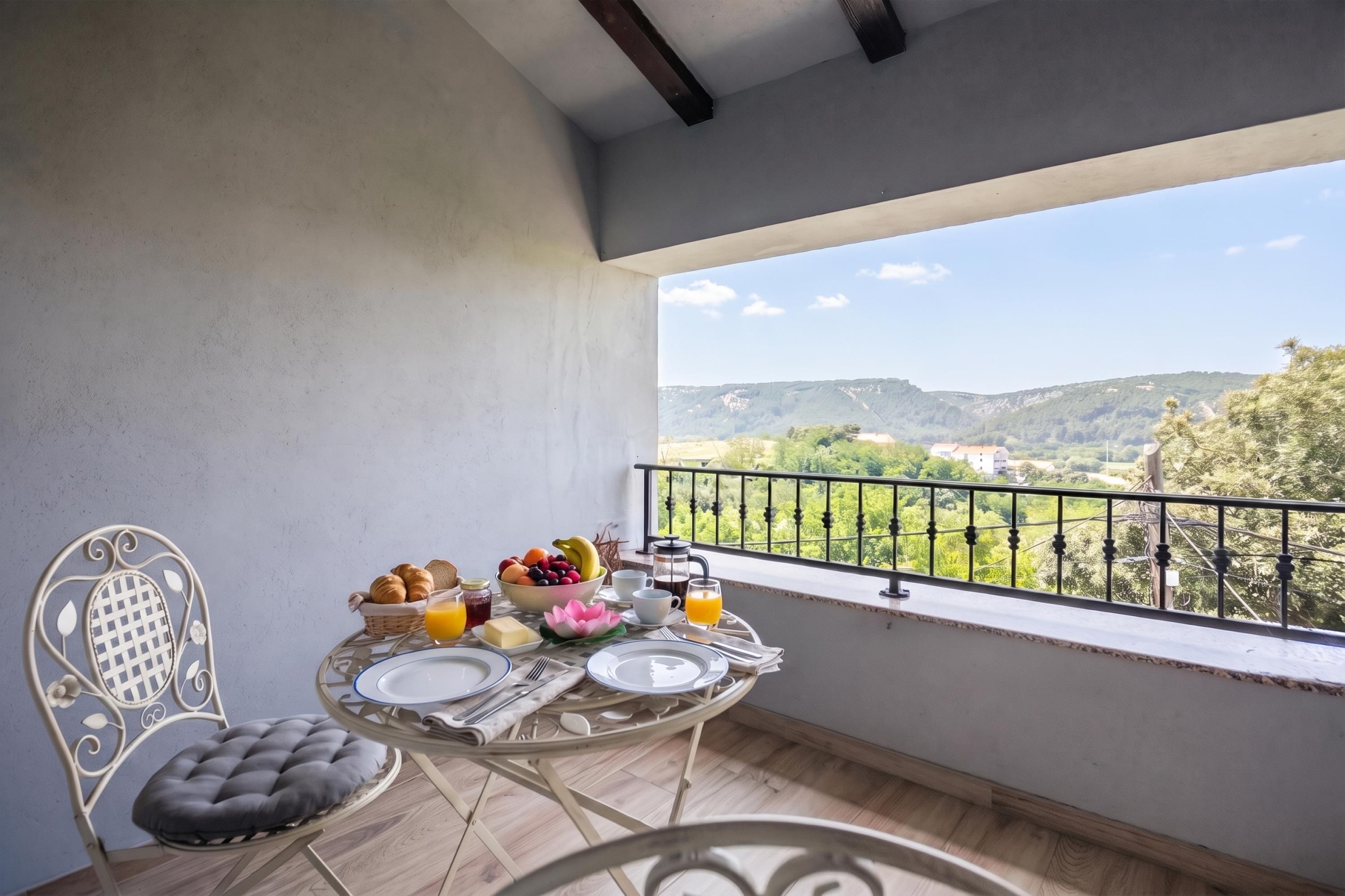 A balcony with a table set for breakfast, overlooking a scenic landscape.