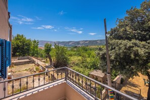 A balcony with a view of a mountainous landscape and a body of water.