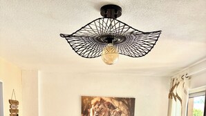 A modern living room with a dark blue sofa, two white side tables, a wall-mounted light fixture, and a framed picture of lions. - Apartment "LA CASA SOL" ☀️ FINE SAND BEACH 1KM 🏝️⛱️🌊 (La Seyne-sur-Mer)
