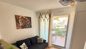 A modern living room with a black sofa, a dining table with plants, and a large painting of lions. - Apartment "LA CASA SOL" ☀️ FINE SAND BEACH 1KM 🏝️⛱️🌊 (La Seyne-sur-Mer)