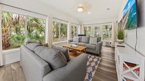 A spacious living room with a grey sofa, a wooden coffee table, and a TV mounted on the wall. - Captain's Quarters by Sandpiper | Near Beach (Seabrook Island)