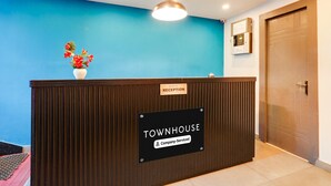 A reception desk with a sign reading "TOWNHOUSE Company Serviced" and a blue wall in the background. - Classic Q Rooms BTM Gopalan Ovation Mall (Bengaluru)