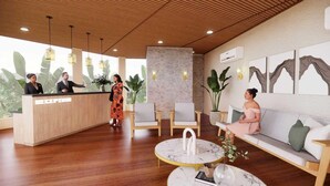 A reception area with a wooden reception desk, a stone accent wall, and a seating area with a sofa and chairs. - Sunday Hotel Dharamshala (Dharamshala)