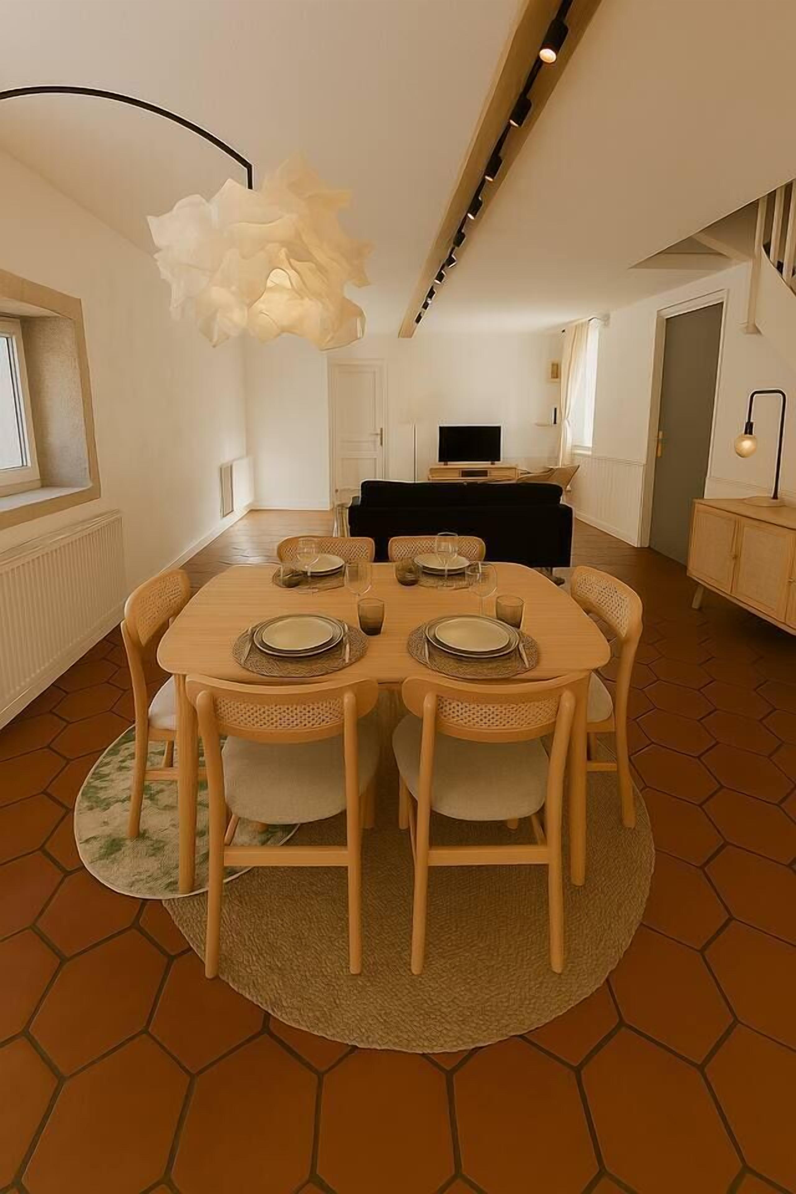 Een eetgedeelte met een ronde tafel, zes stoelen en een hanglamp.