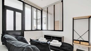 Una habitación de hotel moderna con una cama grande, una mesita de noche con toallas, un espejo y un armario con detalles de madera.