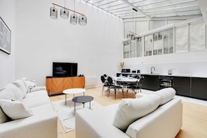 Una sala de estar moderna con un sofá, una mesa de comedor y una zona de cocina con ventana a la ciudad.