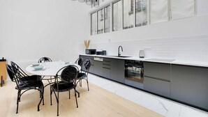 Una cocina moderna con encimera blanca, armarios grises y juego de comedor negro.