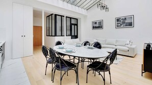 Un área de comedor moderna con una mesa redonda, sillas negras y un sofá blanco.