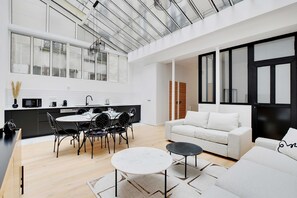 A modern kitchen with a dining area, a living room with a sofa and a coffee table, and a large window with a view of the city. - Authentique Apartment - 1br- 2P- Voltaire (Paris)