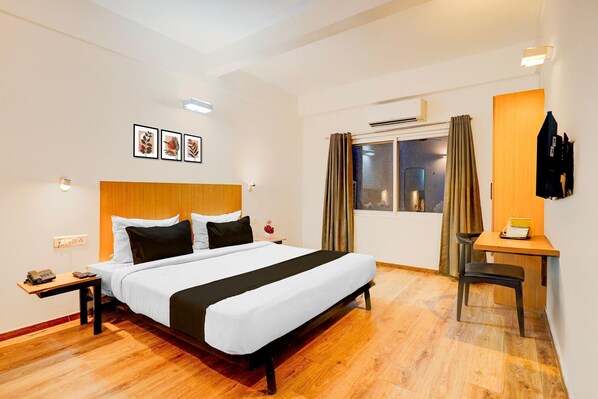 Ein Hotelzimmer mit Bett, Nachttisch, Telefon und Schreibtisch mit Stuhl.