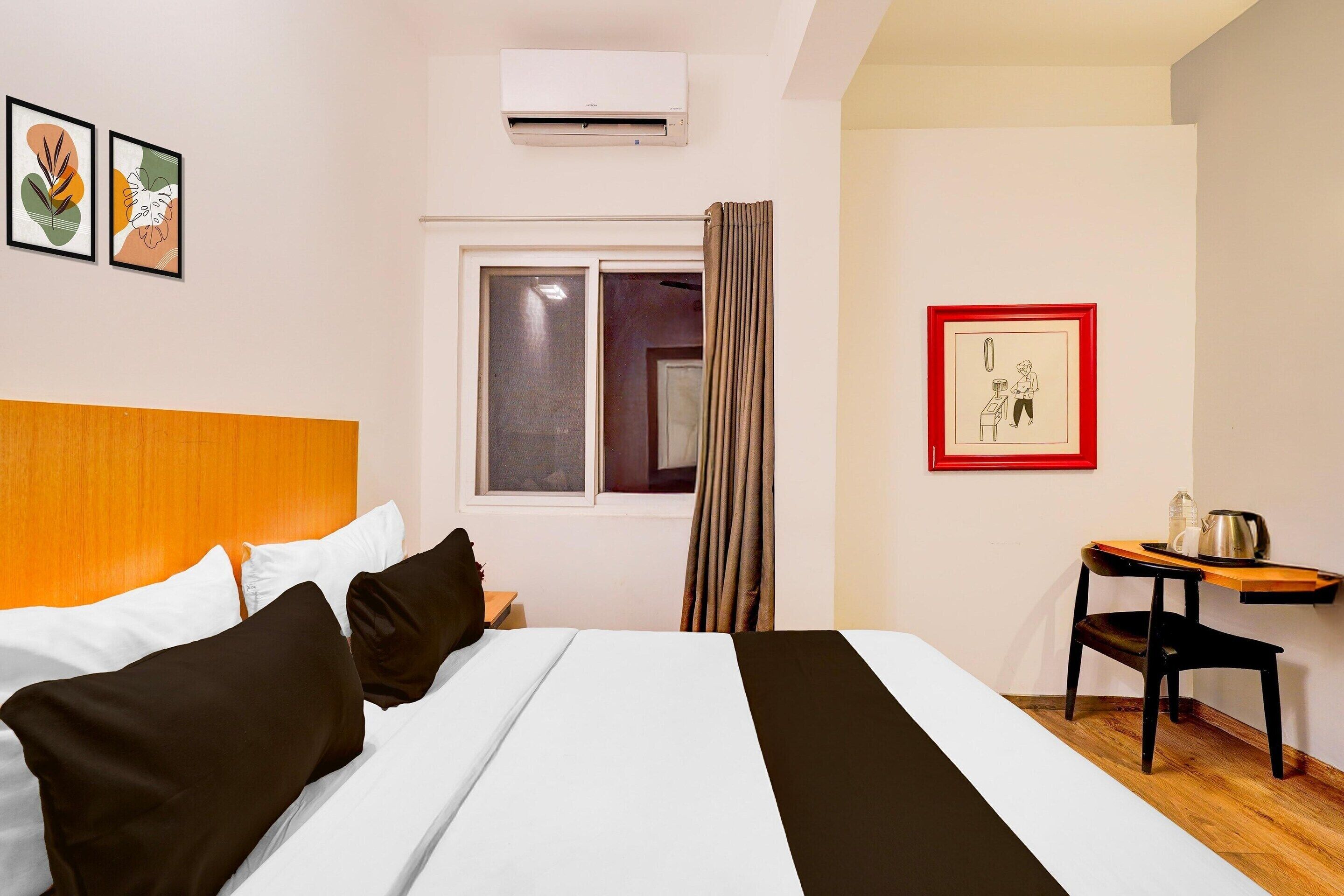 Une chambre d’hôtel équipée d’un lit, d’un bureau, d’une chaise, d’un climatiseur et d’une fenêtre avec des rideaux.
