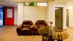 A modern living room with two leather sofas, a glass coffee table, and a red door. - Spacious Comfort Stays Near Aerospace Museum (Bengaluru)