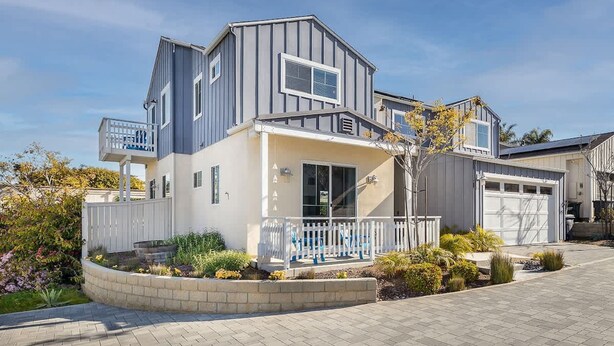Une maison moderne à deux étages, dotée d’un garage, d’un porche abrité et d’un jardin aménagé.