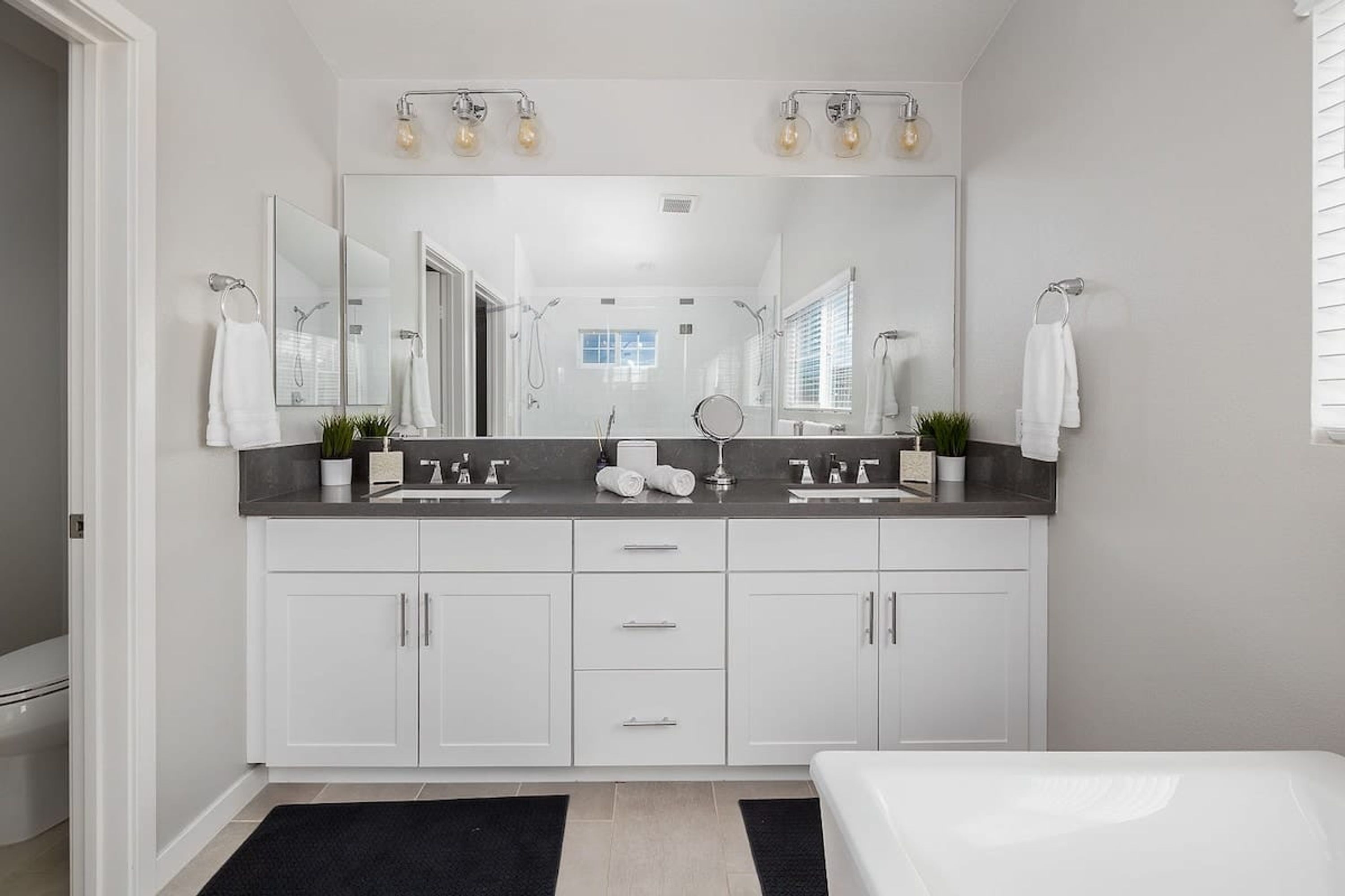 A modern bathroom with a double sink vanity, a large mirror, and a walk-in shower.