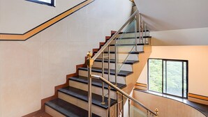 A modern staircase with glass railings and a metal handrail, leading to an upper floor.