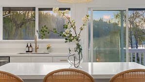 A modern kitchen with a large island, white cabinetry, and a vase with flowers. - 3B2B Upper Unit w/ Oceanfront & Rainier Views (Bremerton)