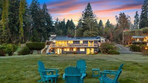 A two-story house with a balcony, surrounded by a grassy yard and trees. - 3B2B Upper Unit w/ Oceanfront & Rainier Views (Bremerton)