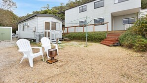 A small house with a gravel yard, two white chairs, and a wooden bench. - Bird and Beach: Close to walking trails leading to the beach and Lake Bunga (Lakes Entrance)