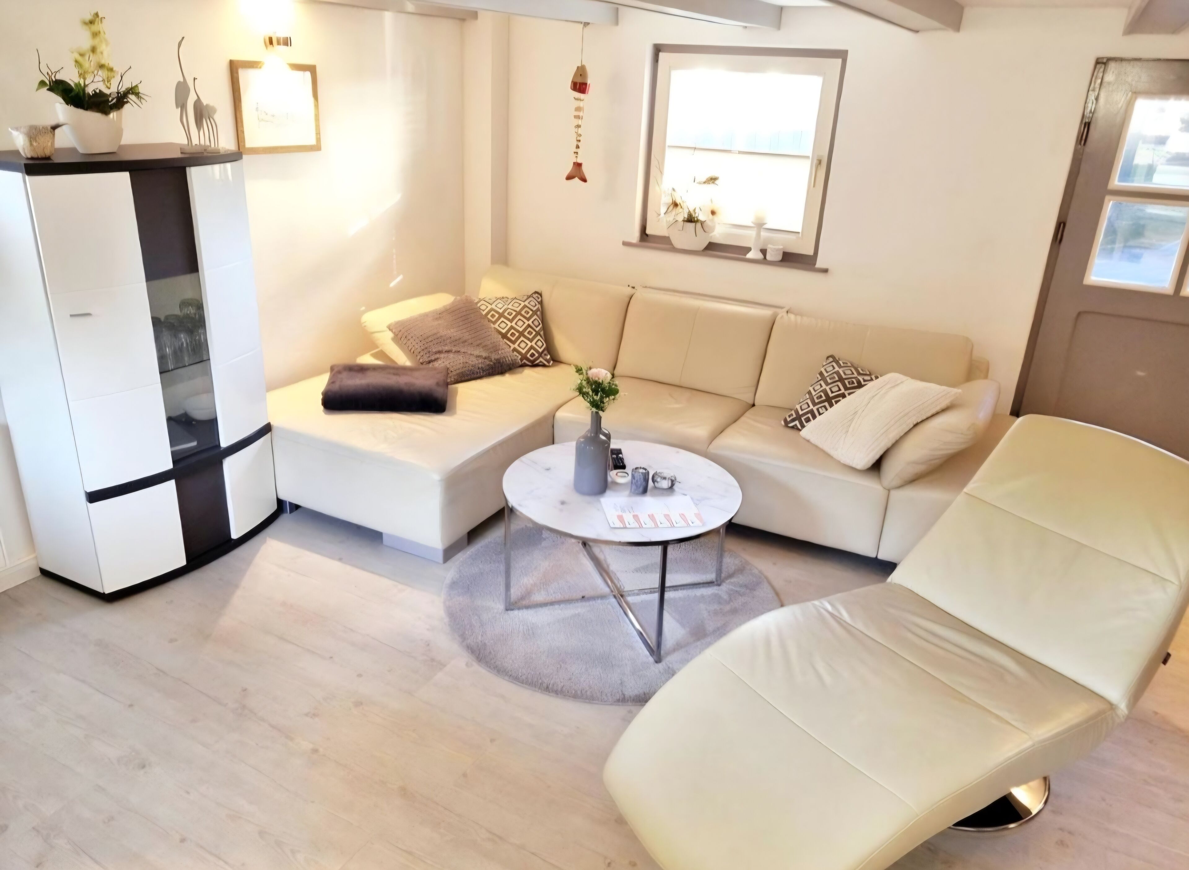 A modern living room with a sofa, a chair, a coffee table, and a white cabinet.