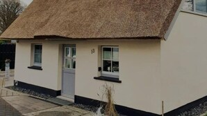 Ein Haus mit einem steilen Dach, einer weißen Fassade und einer kleinen Veranda.