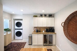 A compact kitchen with a washing machine, coffee maker, and wine cooler.