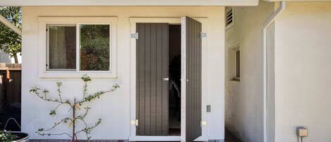 A modern house with a white exterior, a small front yard, and a door leading to the interior.