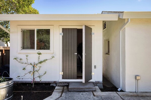 A modern house with a white exterior, a small front yard, and a door leading to the interior.