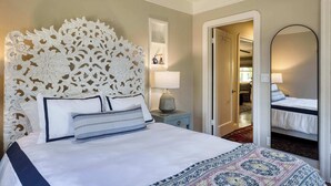 A hotel room with a large ornate headboard, a bed with white bedding and striped pillows, a bedside lamp, and a mirror on the wall. - Stylish Retreat. Grand Private Yard. Fire Pit. A/C (Napa)