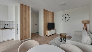 A modern living room with a flat-screen TV, a clock, and a sofa. - Horizon 133 - SeaView by GrandApartments (Gdansk)