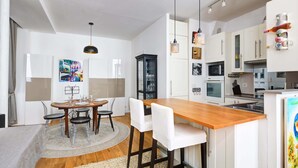 A modern kitchen with white cabinets, a wooden island, and pendant lighting. - Lumunous apartment - 1BDR/5P au coeur du Marais (Paris)