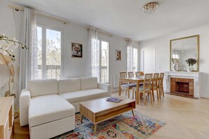 A modern living room with a sofa, coffee table, dining table, chairs, and a fireplace.