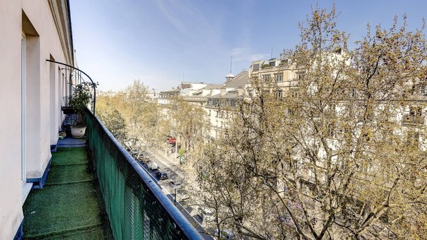 A balcony with a green safety railing overlooking a street with buildings and trees. - BM-Style Parisien a Republique (Paris)