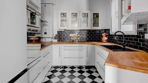 A kitchen with white cabinets, a black and white checkered floor, and a wooden countertop. - BM-Style Parisien a Republique (Paris)